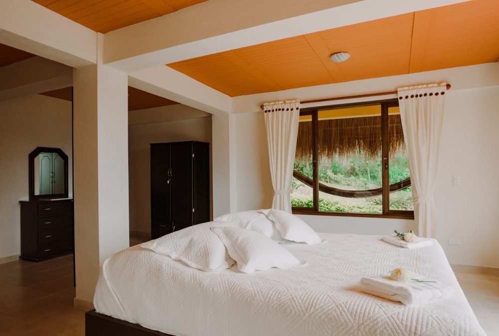 Dormitorio con cama doble con vista a las montañas y una hamaca al lado. Guateque, Boyacá.