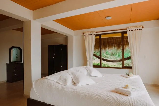 Dormitorio con cama doble con vista a las montañas y una hamaca al lado. Guateque, Boyacá.