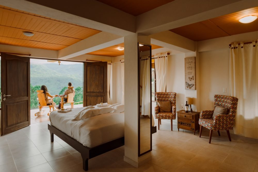 Pareja sentada en mecedoras mirando al Valle de Tenza desde el dormitorio principal del Chalet de Paja.