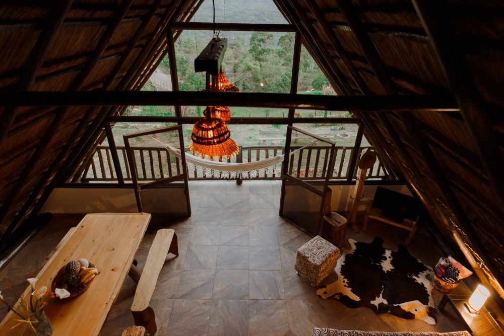 Chalet de paja vista desde arriba, comedor en madera, muebles y lámpara con vista al Valle de Tenza. Guateque, Boyacá.