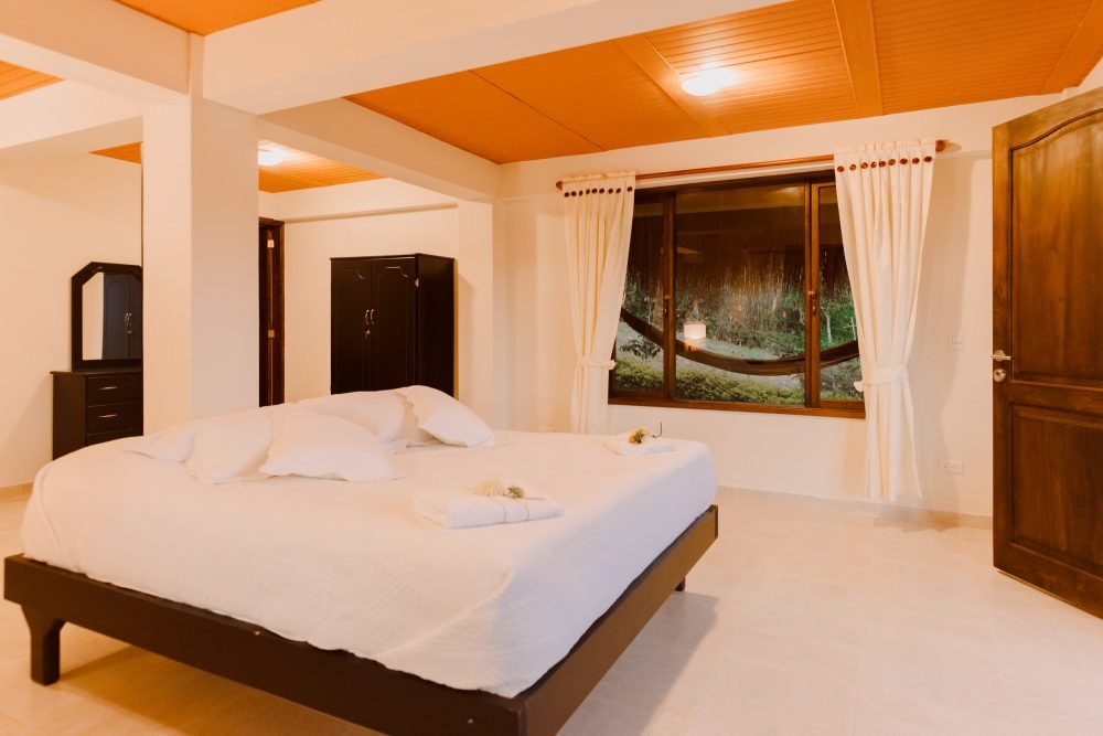 Dormitorio con cama doble, hamaca, acogedora iluminación y armario en Guateque, Boyacá.