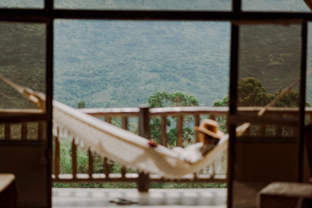 Mujer acostada en una hamaca mirando las montañas del Valle de Tenza desde un Chalet de Paja.