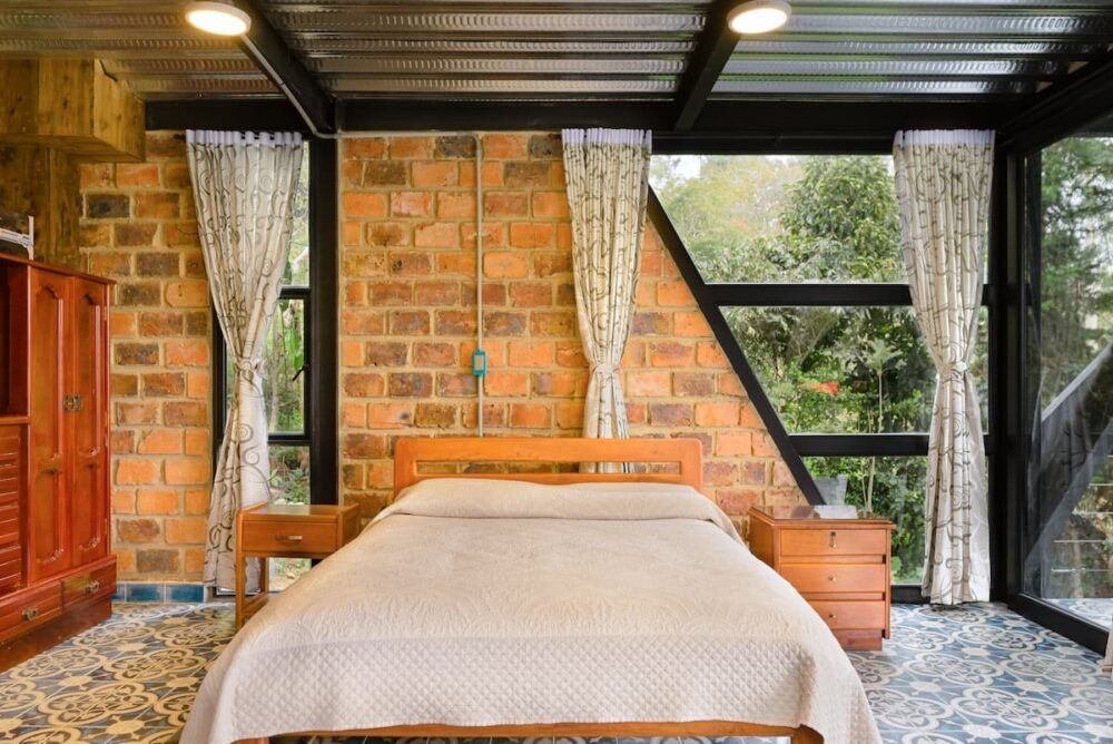 Vista de la cama en El Estudio con paredes de ladrillo. Luciana Cabañas Boutique.